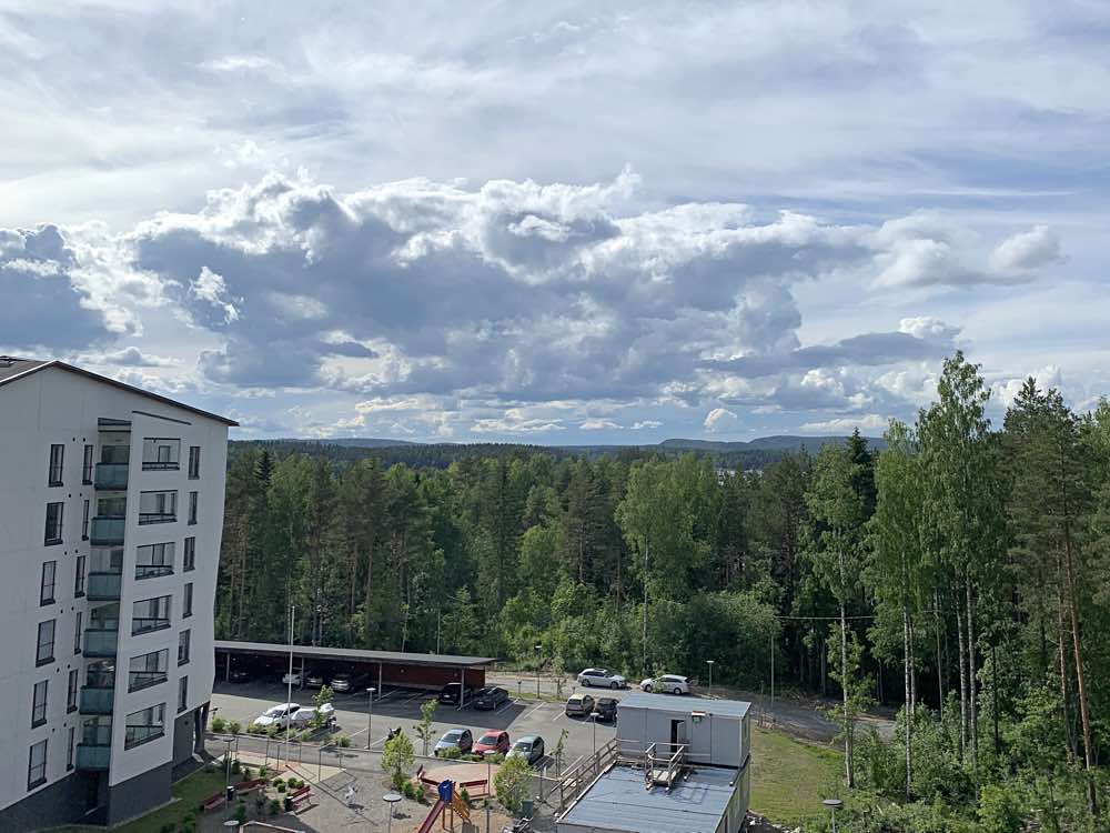 Avara näkymä puiden latvojen yli Asunto Oy Kuopion Kuuran ylimpien kerrosten asunnoista. 